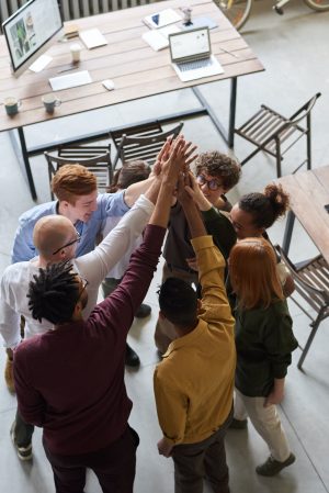 The photo shows a crowd of people raising hands in a group high five. Image credit is by pexels fauxels.